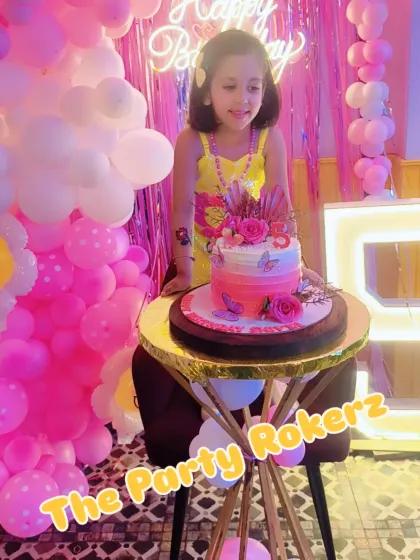 The birthday girl posing with her beautiful cake, which perfectly matches the pink and yellow theme of the party.