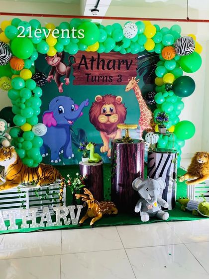 A fun jungle theme for a 3rd birthday, filled with plush animals and a vibrant green balloon arch.