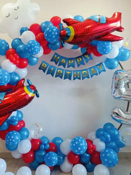A classic airplane-themed 5th birthday. The circular balloon arrangement in red, white, and blue is decorated with large red airplane foil balloons and a "Happy Birthday" banner.