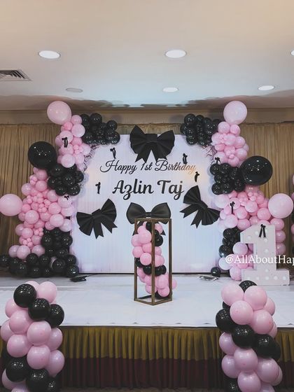 Another angle of the sophisticated bow-themed decor, showing the symmetrical balloon columns and the central display stand, perfect for the birthday cake.