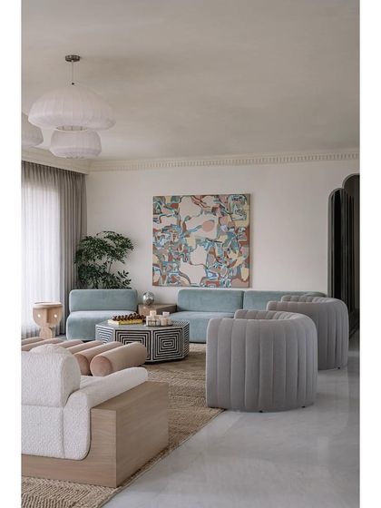 A wide shot of the living room, showing the mix of colorful and sculptural furniture. Each piece feels special, from the face-designed side tables to the custom gradient bar.