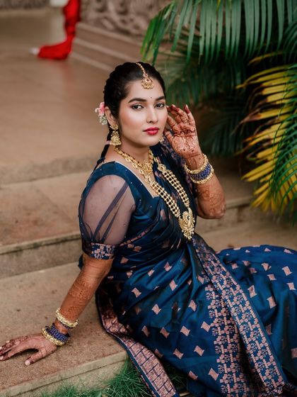 A beautiful full-length bridal portrait, showcasing the bride's elegant blue saree and traditional jewelry.
