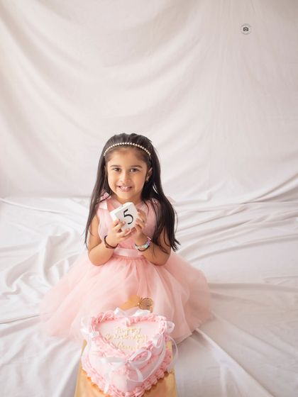 A sweet heart-shaped cake for a fifth birthday girl. Her joyful smile is the centerpiece of this simple and lovely birthday portrait.