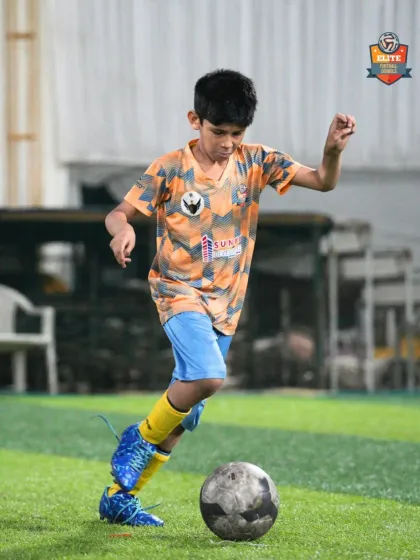 A young player dribbles with his head up, looking for a teammate to pass to.