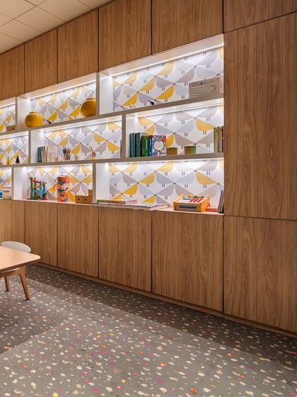 The built-in shelving in the Elevate kids' area, featuring playful wallpaper and integrated lighting. This detail combines functional storage with a whimsical design element.