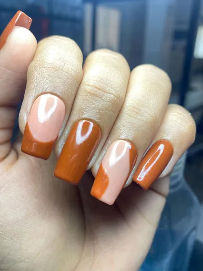 A modern take on a French manicure, using a deep orange color and a creative, curved smile line. This is a great example of how to update classic styles.