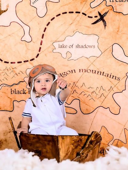 A baby dressed as a pilot, pointing towards the horizon on a treasure map. This shot captures a sense of wonder and exploration.