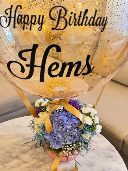 My signature hot air balloon arrangement is a client favorite. Here, I paired a beautiful box of blue hydrangeas, white roses, and carnations with a custom gold-flecked bubble balloon for a special birthday celebration.