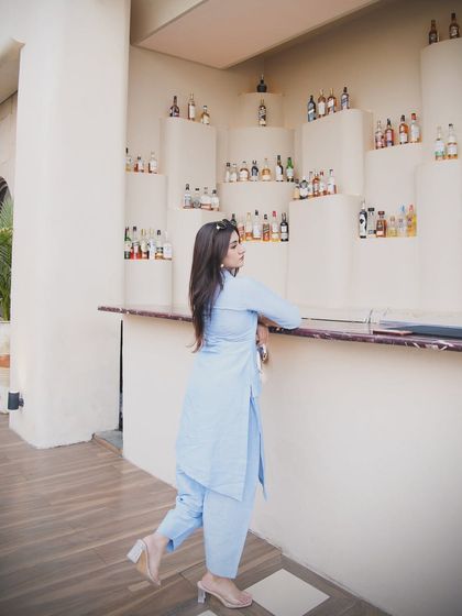 A side profile shot in the same powder blue suit, leaning against a bar. It shows the clean lines and classic appeal of the outfit.