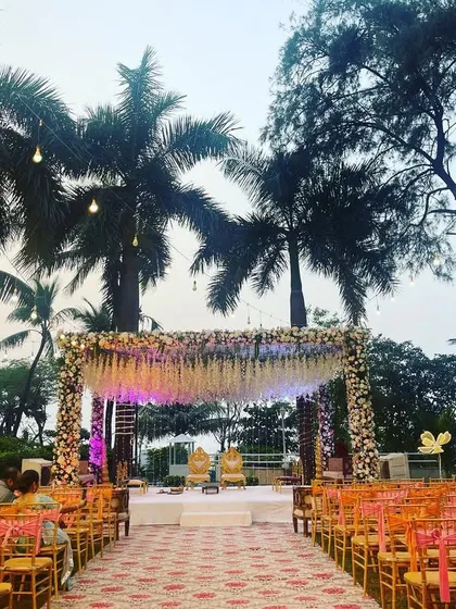 A beautiful mandap with a canopy of cascading white flowers set against the palm trees. This setup is perfect for a daytime or sunset wedding, creating a soft and romantic ambiance.