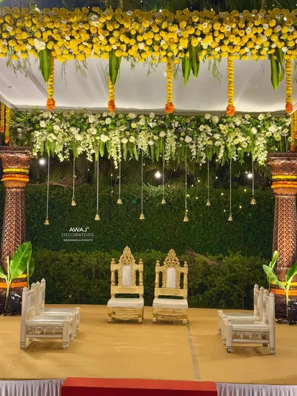 A detailed shot of the couple's seating within the mandap, framed by hanging bells and a beautiful floral canopy.