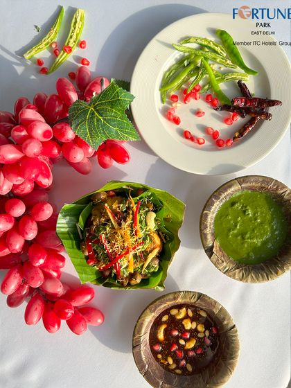 A vibrant and healthy dish served in a banana leaf bowl, accompanied by fresh chilies, pomegranate seeds, and two distinct chutneys.