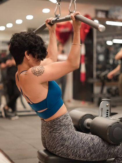 With a tattoo on her shoulder, this member shows her strength and style while performing lat pulldowns.
