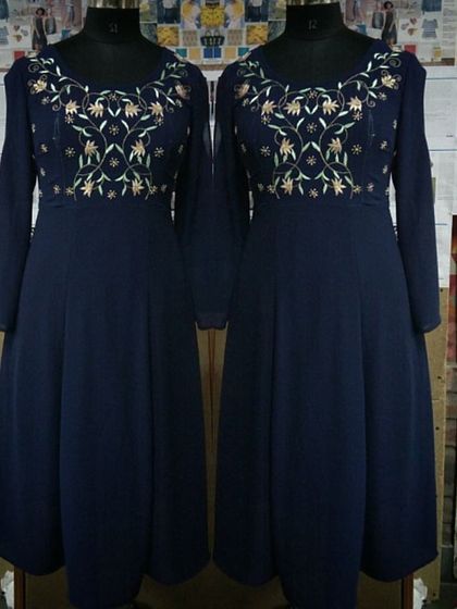 A full-length view of a navy blue Anarkali-style dress on a mannequin. The intricate gold embroidery on the yoke provides a beautiful contrast, making it an elegant option for evening festivities.