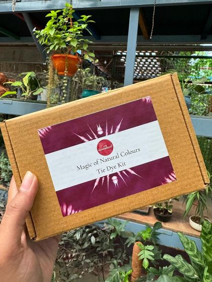 My 'Magic of Natural Colours' tie-dye kit, held against a lush green background. This DIY kit has everything you need to start your own natural dyeing adventure at home.