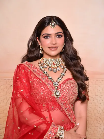 A beautiful front-facing shot of a traditional red bridal look, created by a student. Notice the clean base and perfectly blended eye makeup.
