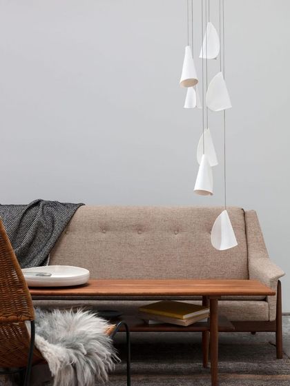 A small, sparse arrangement of Bocci 21 pendants hangs over a mid-century modern sofa, demonstrating a more minimalist approach to the series.