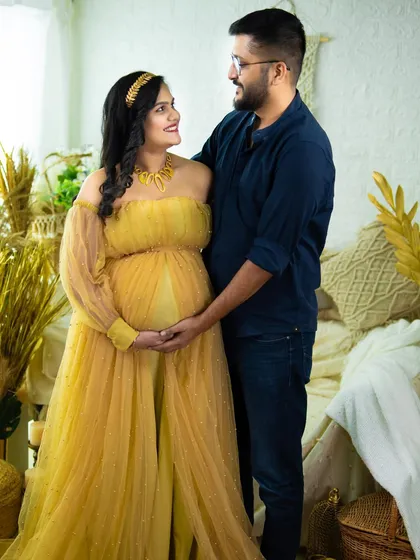 A beautiful couple's portrait in our boho studio. The mom-to-be, in a stunning yellow gown, shares a loving look with her partner.