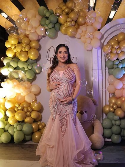 The glowing mom-to-be posing in front of her baby shower backdrop. The soft lighting and bubble effects create a magical ambiance for photos.
