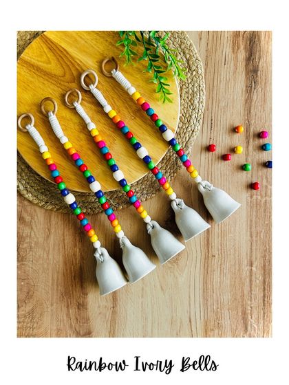 Introducing our 'Rainbow Ivory Bells'. These adorable mini ceramic bells in a soft white ivory are handmade with a pop of color from cheerful wooden beads, adding a touch of whimsical charm to any space.