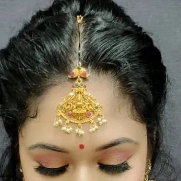 A detailed close-up of the eye makeup and traditional temple-style maang tikka, showcasing the precision taught in our classes.