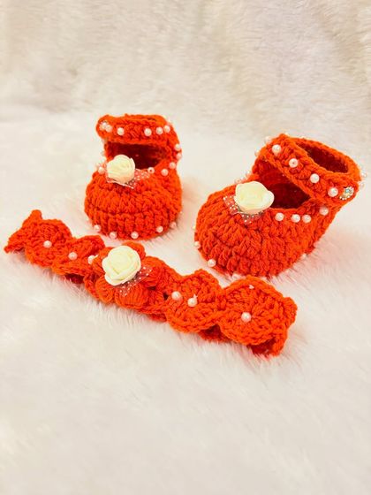 This vibrant orange set includes Mary Jane-style booties and a matching headband, both decorated with pearls and a small white rose.
