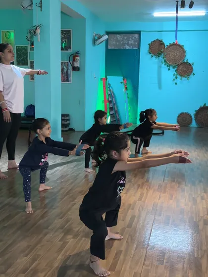A group of young dancers practicing their plié squats in unison. This exercise is fundamental for building lower body strength and stability.