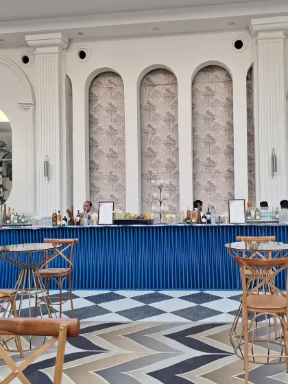 A long, stylish bar setup against a classic white paneled wall, with a striking blue and white checkered floor.