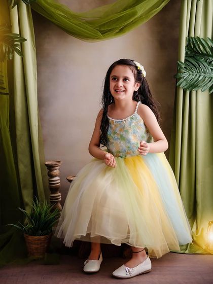 A happy, smiling fairy in a pastel rainbow dress, enjoying the magic of our enchanted forest studio setup.