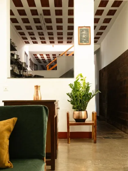 A glimpse from one space into another, showing the continuity of the waffle slab ceiling and the use of plants and simple furniture to create a warm, inviting atmosphere.