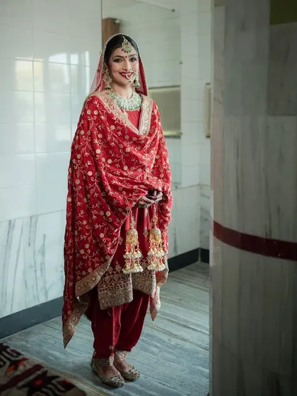 A full view of the best Punjabi bride. Her smile and the classic red suit with beautiful kaleeras make for a perfect and traditional Anand Karaj look.