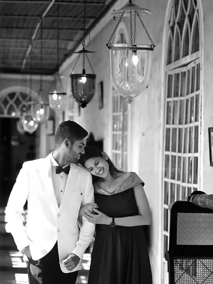 A timeless black and white pre-wedding portrait in a heritage location. The classic monochrome edit emphasizes the couple's connection and the architectural details of the corridor.