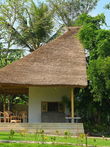 The reception hut at Fireflies Resort features a traditional thatched roof and bamboo supports, nestled among lush greenery. This structure serves as a welcoming entry point, immediately setting a tone of rustic, nature-focused hospitality.