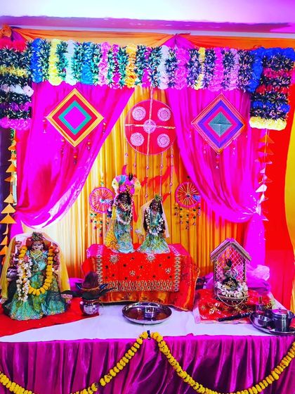 For a Janmashtami kirtan, I created this colorful backdrop for the deities. The setup uses bright pink and yellow drapes, traditional Rajasthani hangings, and a decorated table to form a small temple space.