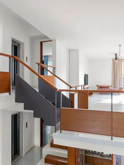 The multi-level circulation in the 'Copper House' is a key part of its design. This view shows how the staircases and bridges connect different zones, with wood and steel railings creating clean lines against the white walls.