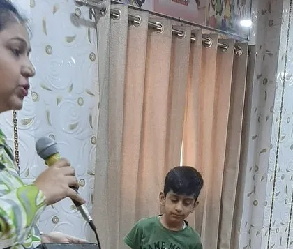 An instructor holds the microphone for a young student, encouraging him to speak in front of his peers during our personality development workshop.