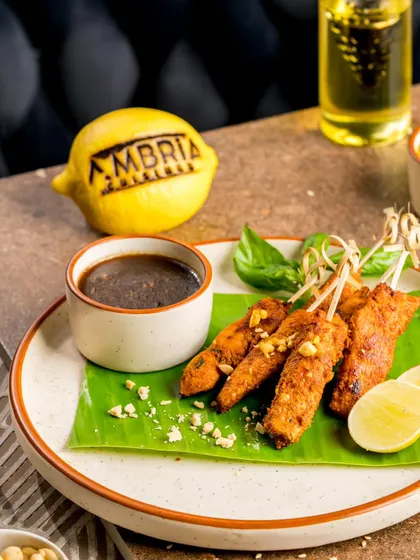 Classic Thai Chicken Satay skewers, grilled and served on a banana leaf with a rich and nutty peanut dipping sauce.