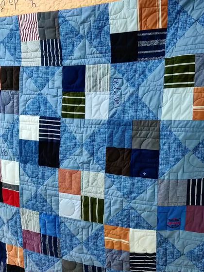 Another t-shirt memory quilt, this one using a blue color scheme and featuring words like "love" and "believe" quilted into the design.