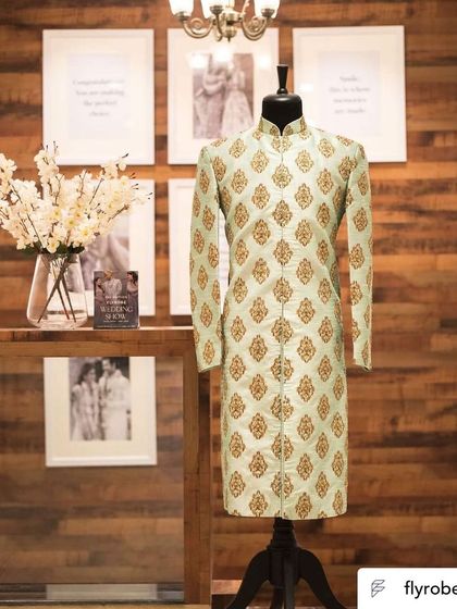 A mint green sherwani with gold butti work displayed on a mannequin. This piece shows our range of pastel options for modern grooms.