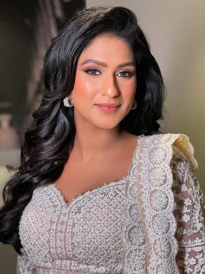 A perfect sangeet look with side-swept voluminous curls. This style is elegant and keeps the hair off one side of the face to highlight earrings.