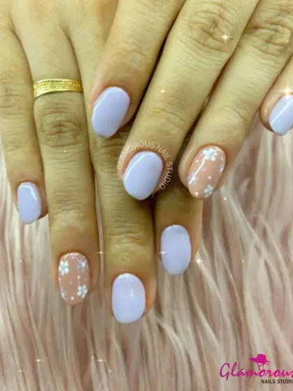 A delicate and pretty design featuring soft lavender nails paired with sheer accent nails adorned with tiny white daisies.