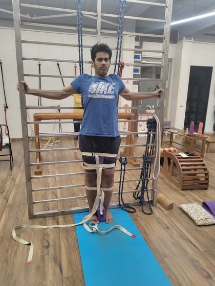 A young student using belts and a block to correct leg alignment in Tadasana (Mountain Pose). This is foundational work to build awareness from the feet up.