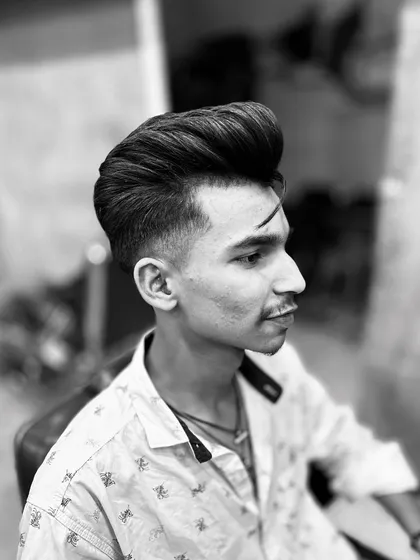 This black and white shot highlights the structure of a great haircut. Notice the smooth gradient of the fade, the volume in the pompadour, and the sharp line of the eyebrow slit.