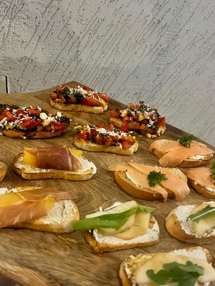 Our bruschetta platter offers a variety of toppings to please every palate. This board features classic tomato and basil, prosciutto with melon, smoked salmon, and pear with cheese, showcasing the quality ingredients we use.