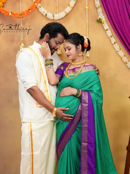 A beautiful portrait capturing the connection between an expecting couple in traditional South Indian attire. The festive backdrop with marigold flowers adds a celebratory feel to the moment.