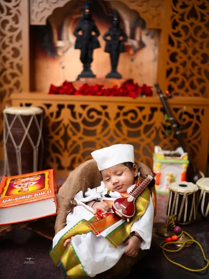 A sleeping newborn holds a miniature sitar in this Varkari-themed setup. Every prop is carefully chosen to create a complete and heartwarming story.