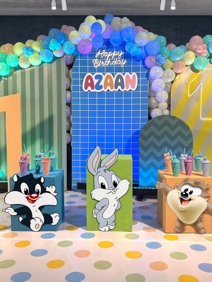 A playful and colorful Looney Tunes baby theme. This design for Azaan's first birthday features pastel colors, multiple patterned backdrops, and cute baby versions of Bugs Bunny, Taz, and Sylvester.