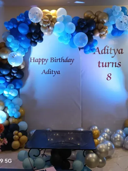The same stylish blue, black, and gold balloon arch, shown from a slightly different angle to highlight the color combination.