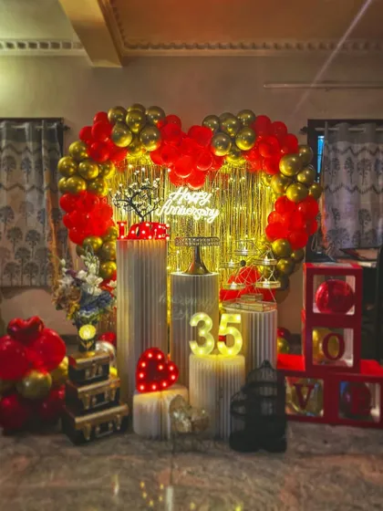I design romantic setups to celebrate your special milestones together. This 35th anniversary decoration features a heart-shaped balloon arch in bold red and chrome gold, set against a golden shimmer curtain. The package includes a 'Happy Anniversary' neon sign, marquee numbers, and a variety of lit props like the 'LOVE' sign and a miniature tree to create a warm, intimate feel.
