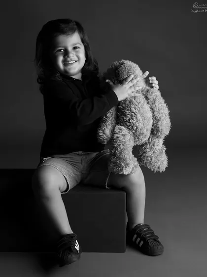 A classic black and white portrait of a boy hugging his teddy bear. This timeless shot focuses on the sweet connection and emotion of childhood.